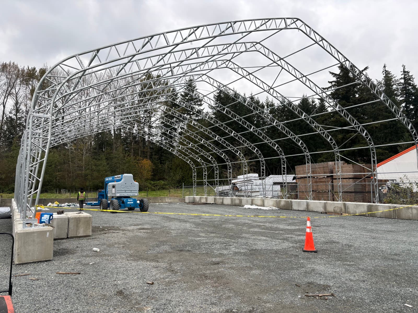 Steel arch structure frame being assembled with a boom lift on site.