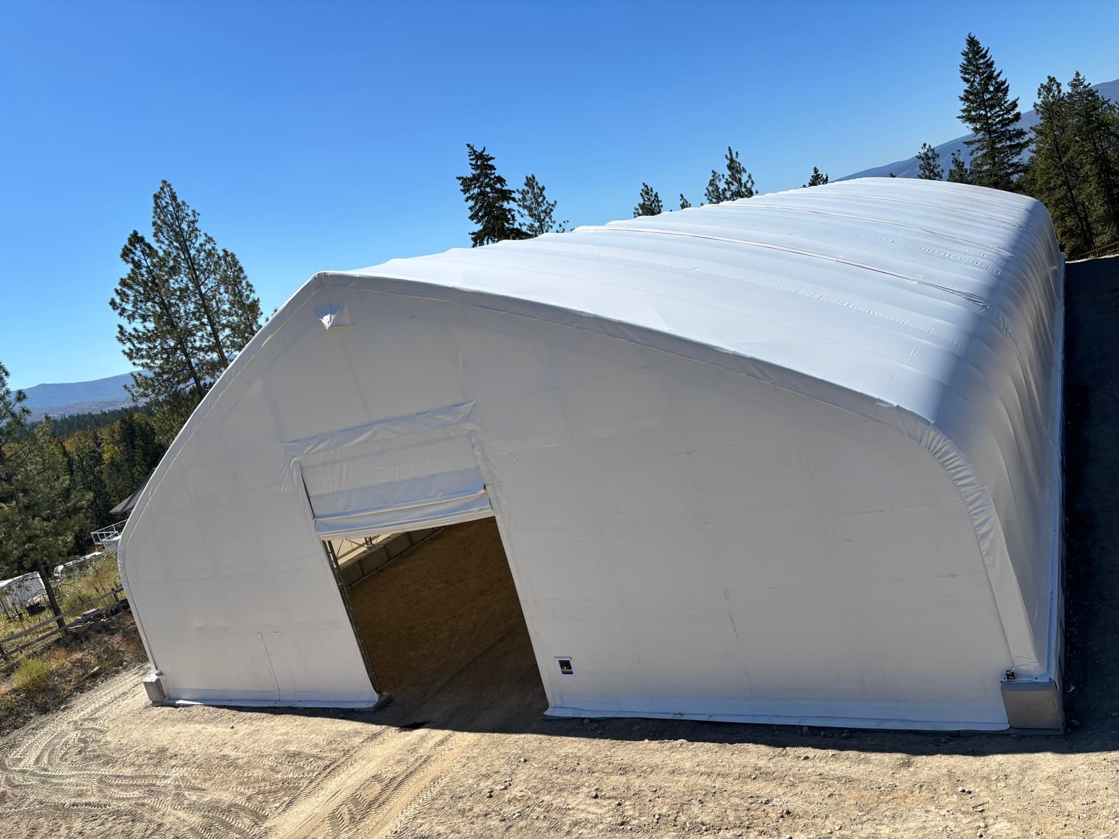Completed fabric-covered arch building under a clear British Columbia sky.