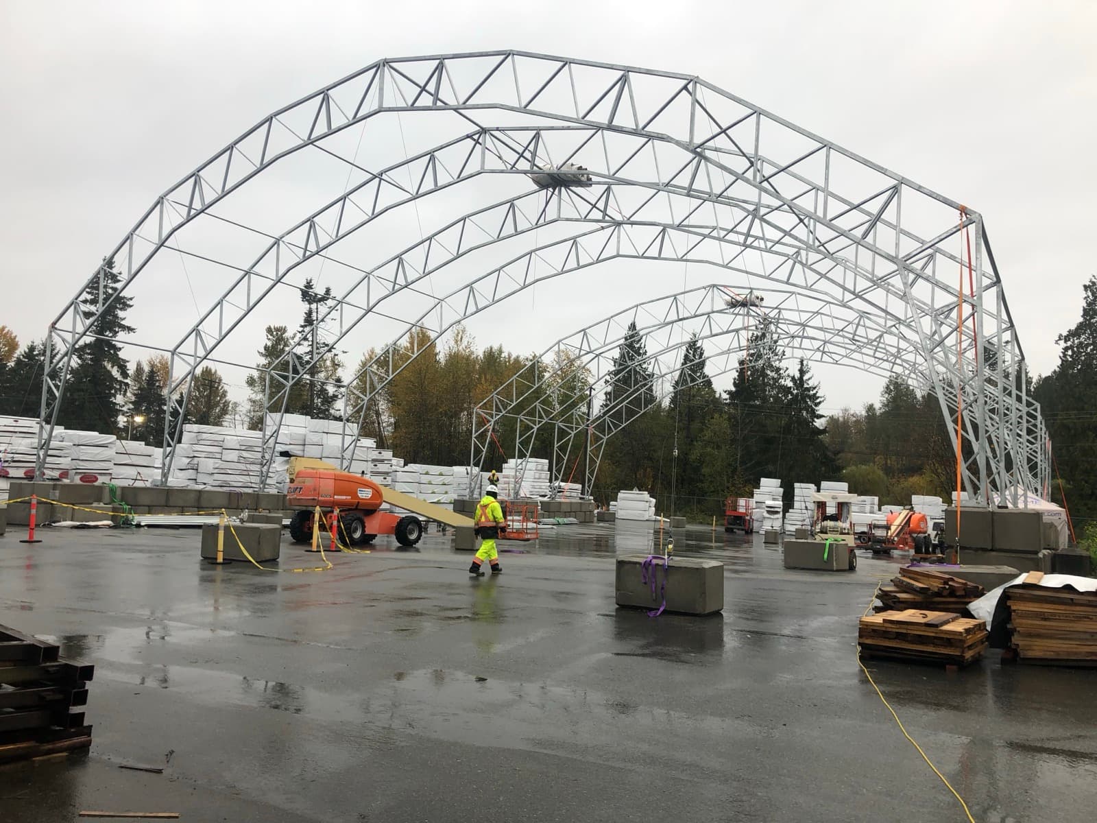 Steel arch building frame being installed in active weather conditions.