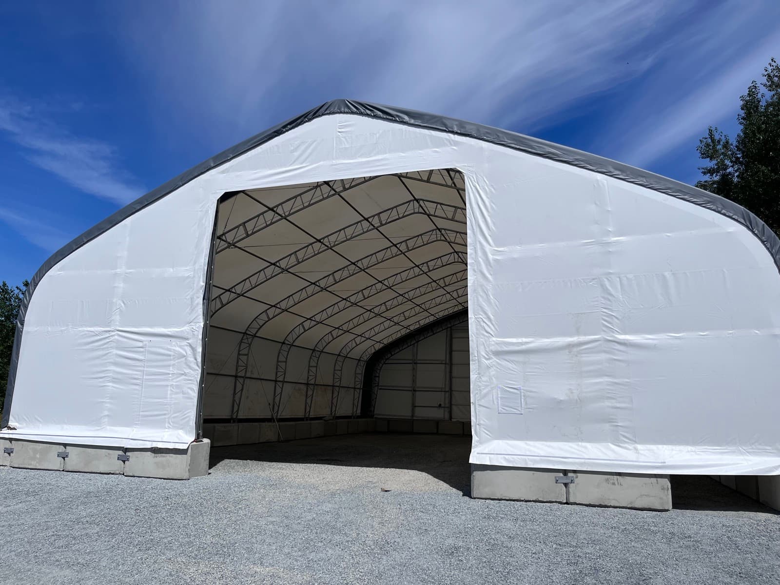 Interior of a fabric-covered building showing the installed steel truss frame.