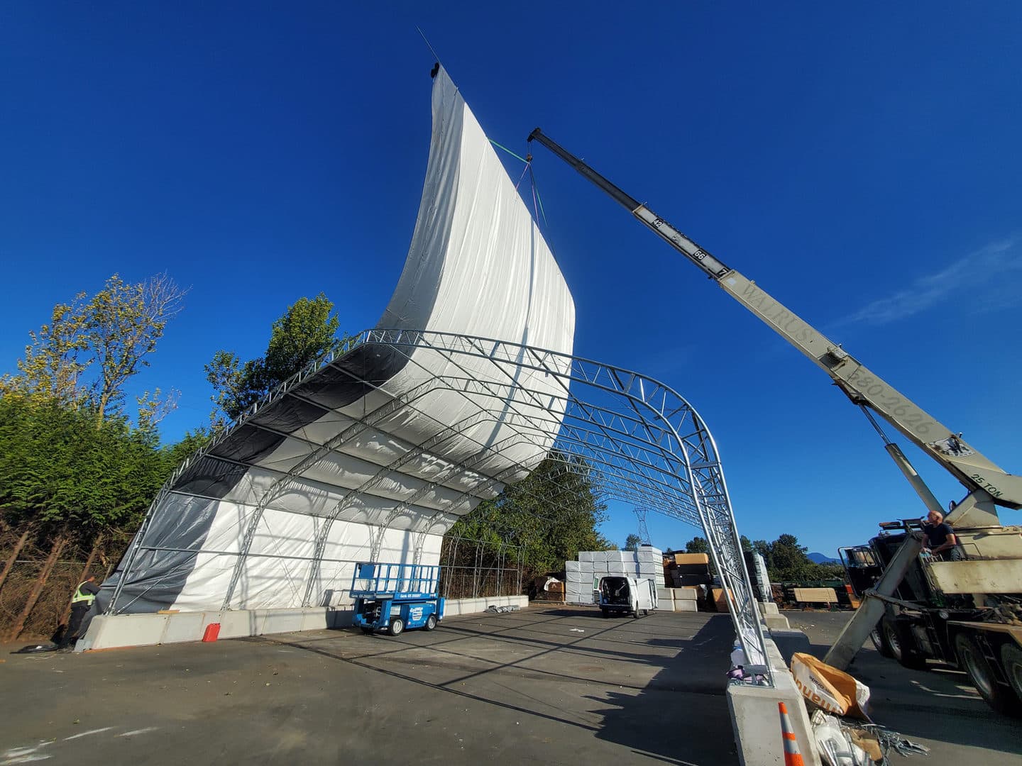 Fabric cover being lifted over a structural frame.