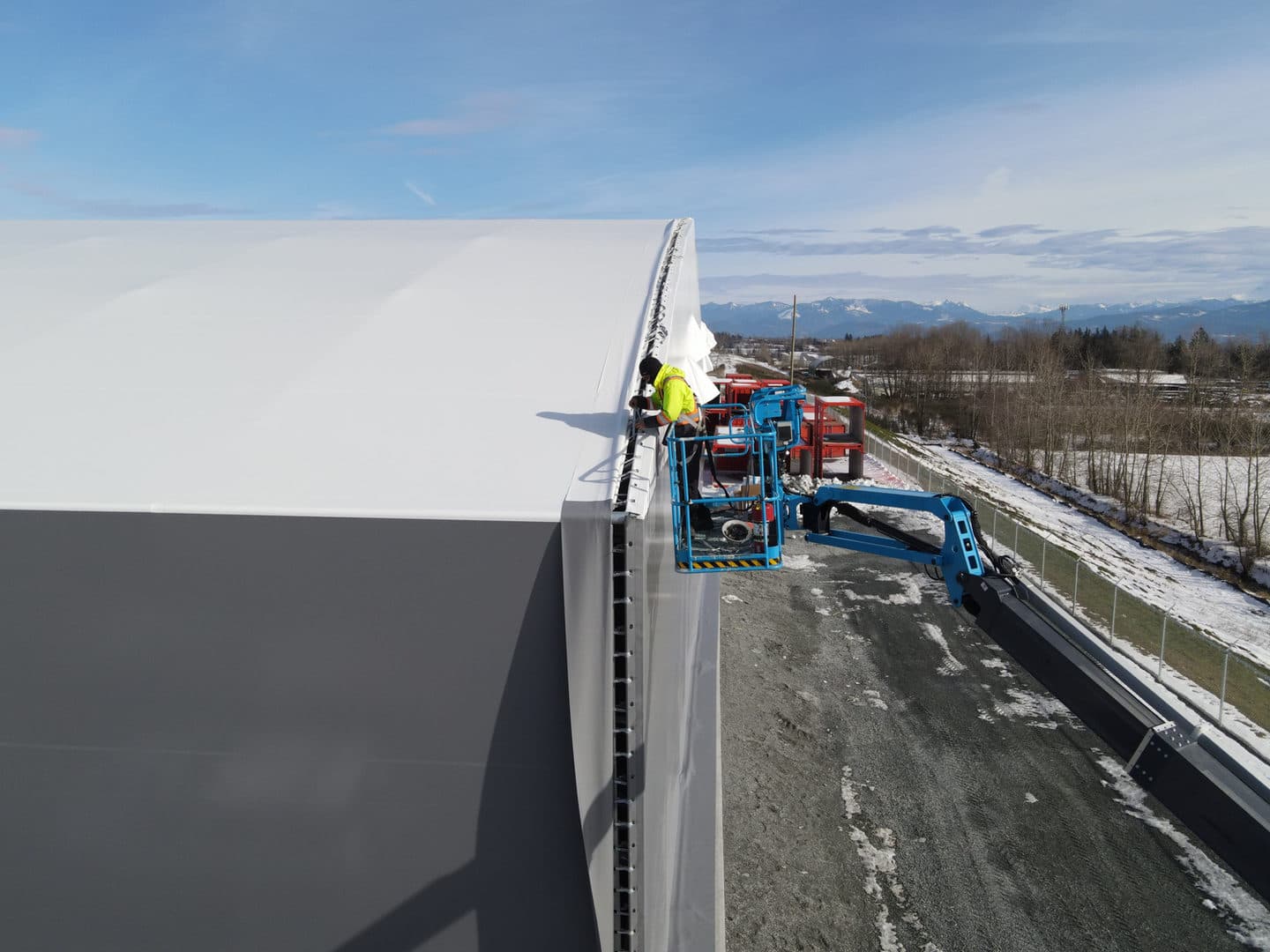 Worker using a boom lift to complete structure installation details.